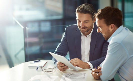 Two professional men reviewing a digital tablet during a business consultancy meeting.