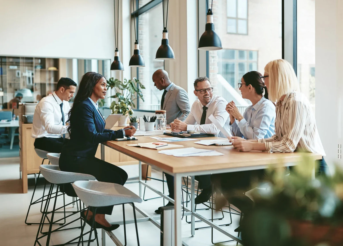 Diverse professional team having a business meeting around a large wooden table in a modern office.
