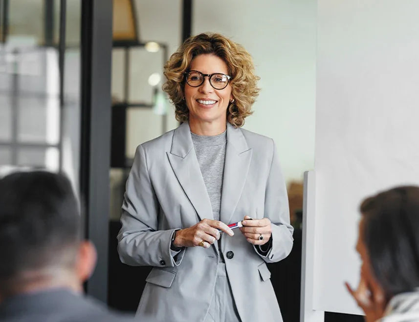 Smiling female executive coach presenting to a team in a professional workshop setting.