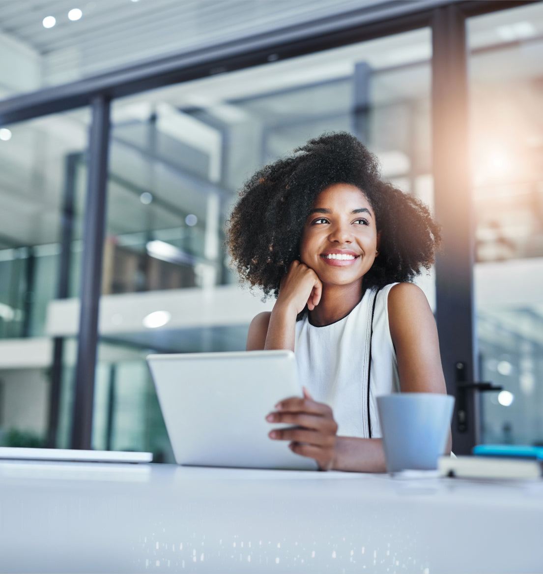 Smiling professional woman using a tablet in a modern office setting.