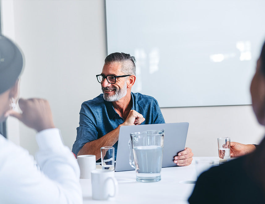 Smiling businessman with glasses leading a professional team meeting in a bright office.