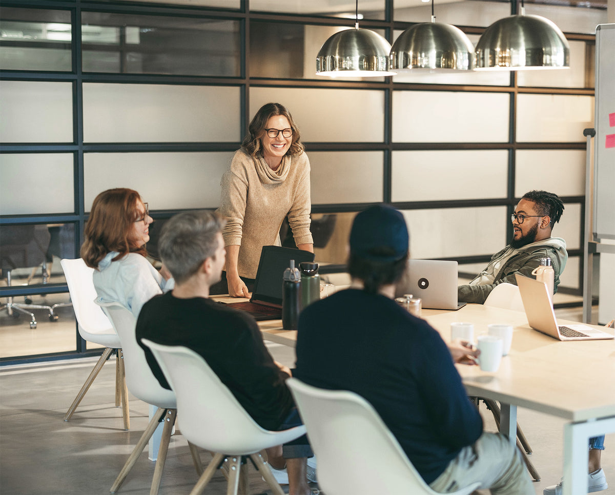 A female leader presenting to a diverse team during a business meeting in a modern office.